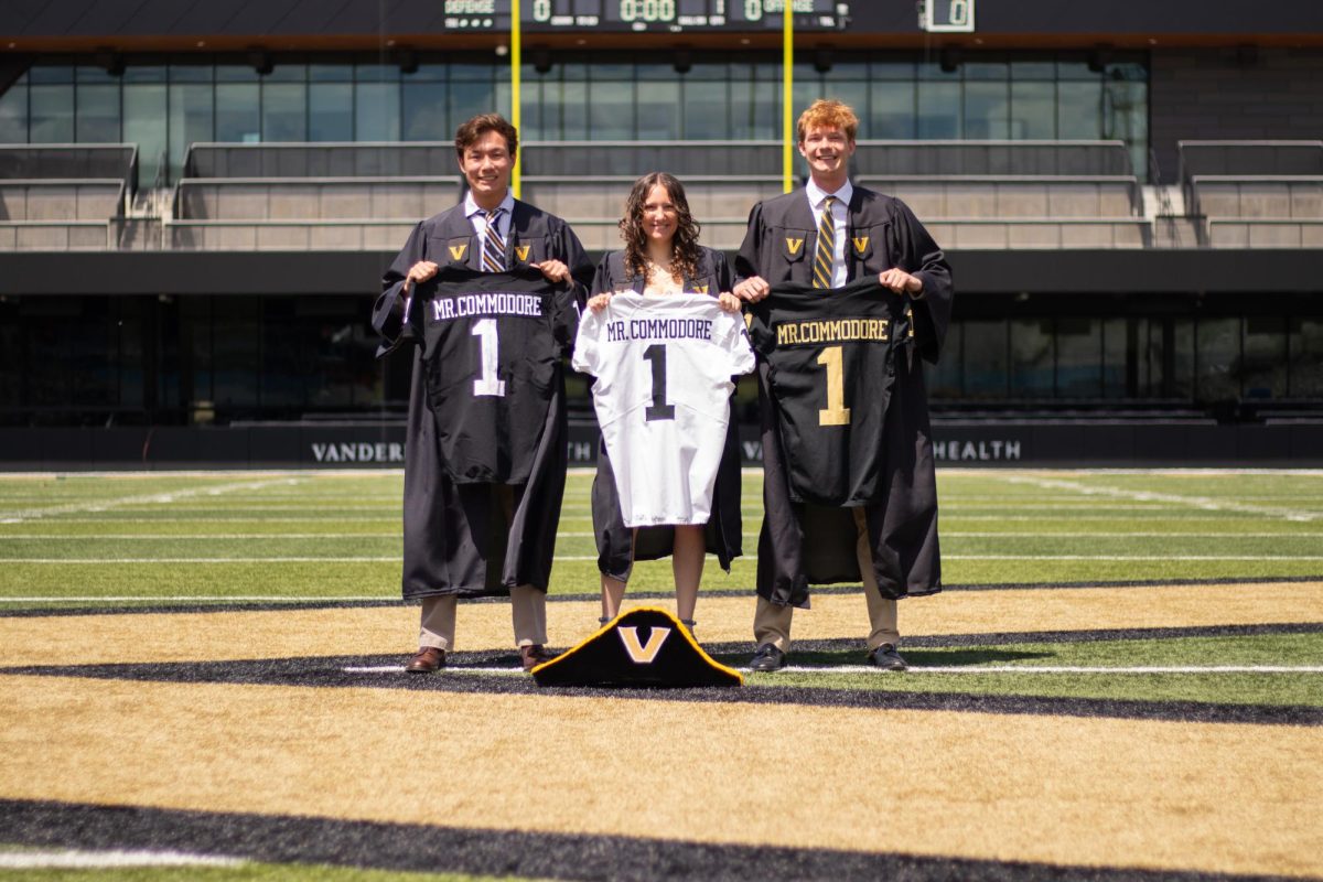 From left: Kaleb Whiteside, Kira Grossman and Sean Richardson wear graduation gowns and hold Mr. Commodore jerseys. (Hustler Staff/Connor Campbell)
